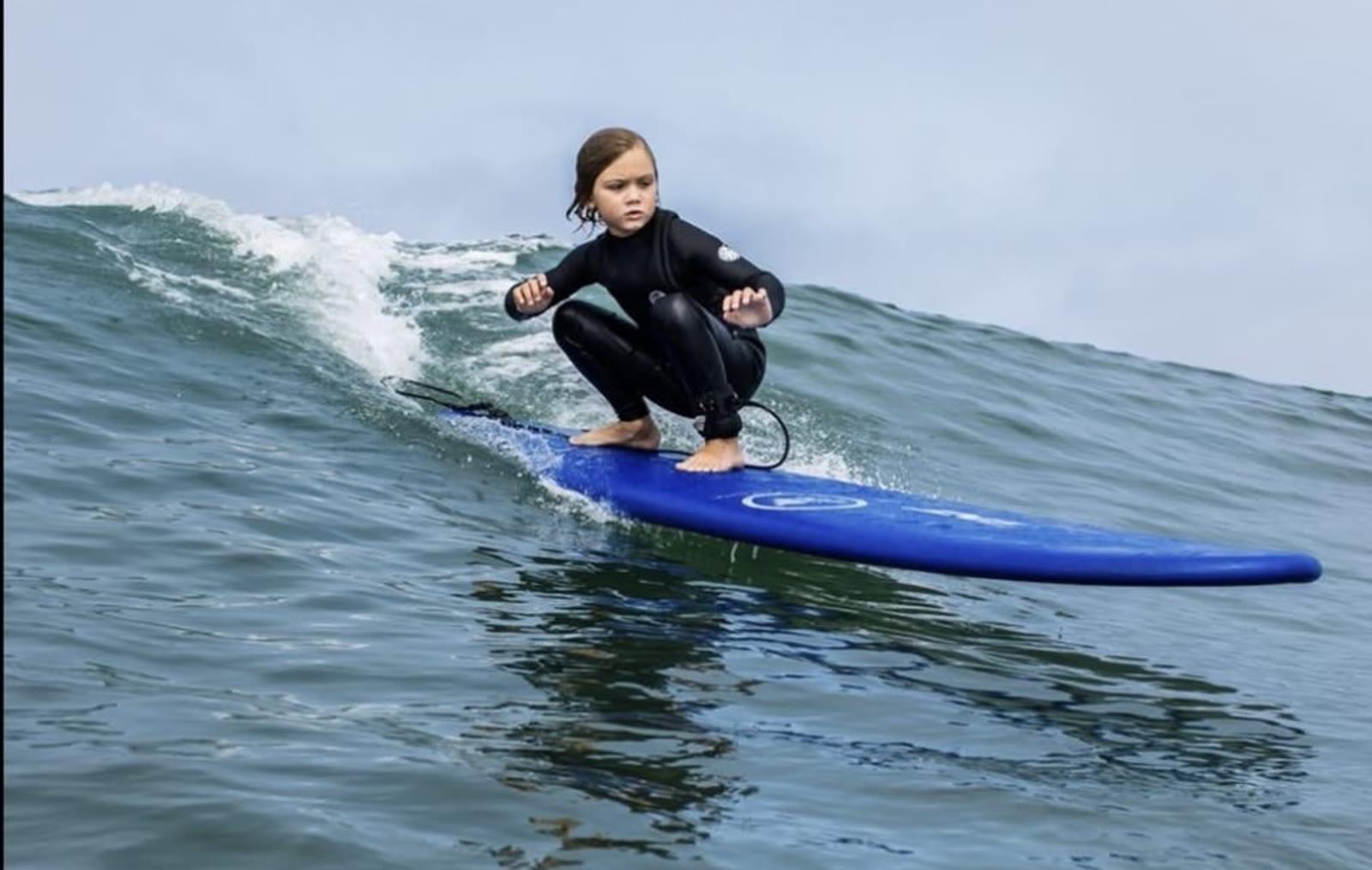 Young surfer crouched on a longboard